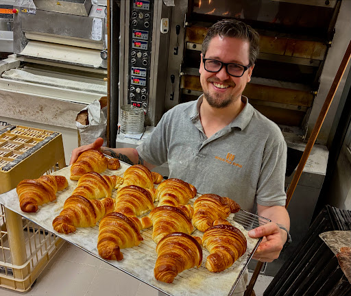 Loïck dans le fournil, une plaque de croissants dorés à la main